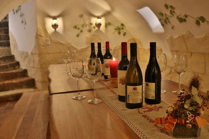 Tisch in Weinkeller, dekoriert mit Weinflaschen und Weingläsern